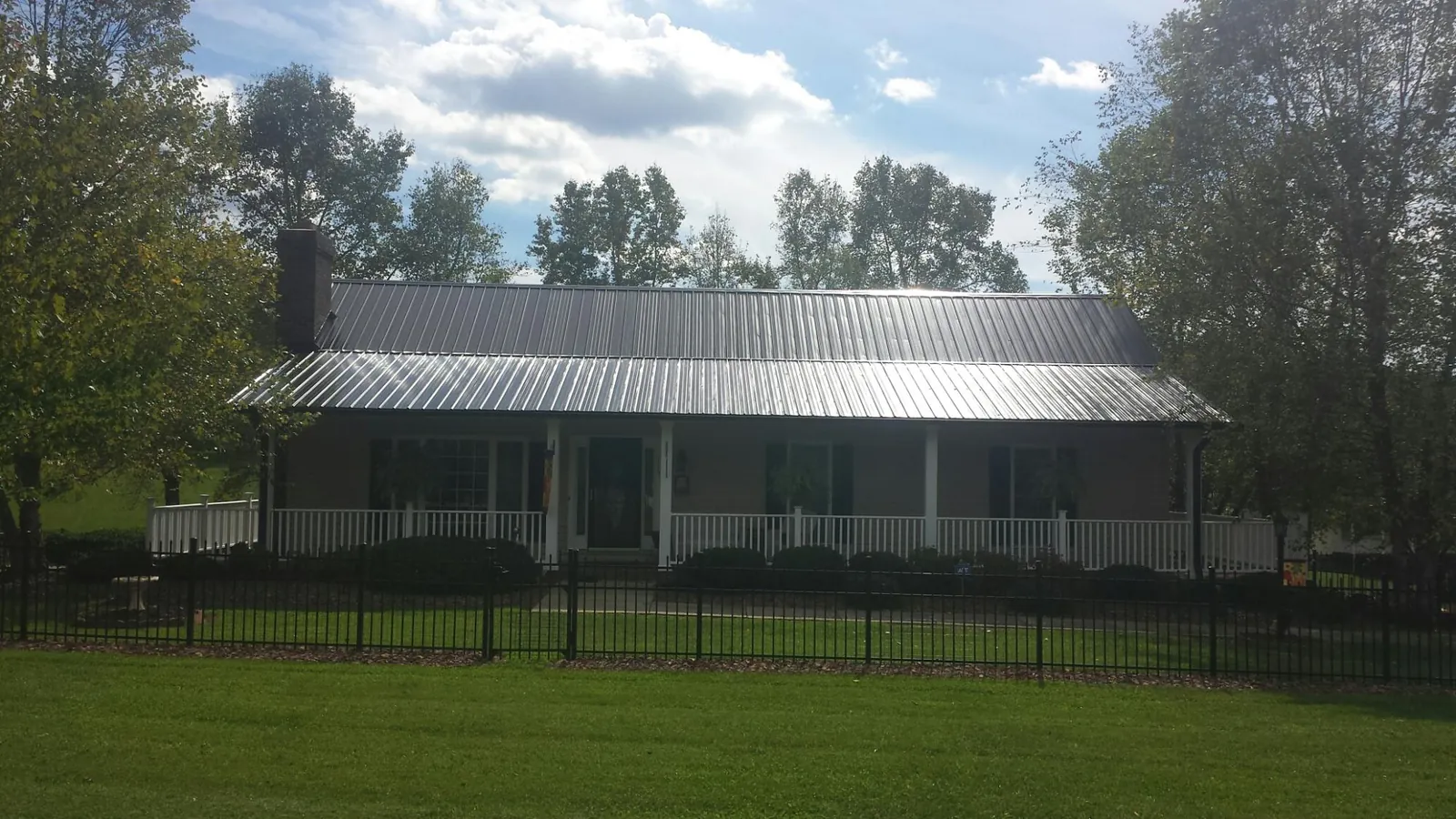 Gray metal roof on a brick ranch with a full width front porch — Gutter Guard Installation work by our crew in Etna